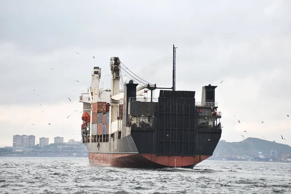 Cargo ship in harbor logos and brandnames systematically removed