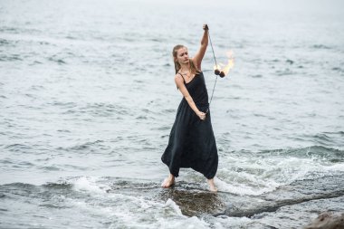 Alevli meşalelerle siyah elbiseli kız .