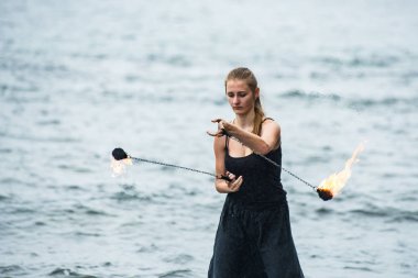 Alevli meşalelerle siyah elbiseli kız .