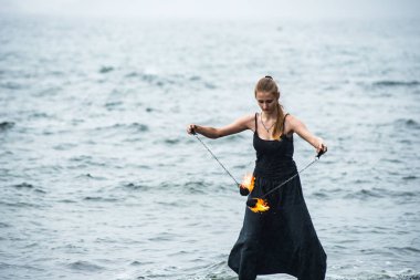 Alevli meşalelerle siyah elbiseli kız .