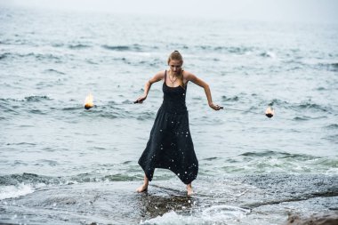 Alevli meşalelerle siyah elbiseli kız .