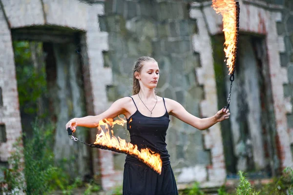 Girl in a black suit with flaming torches . — Stock Photo, Image