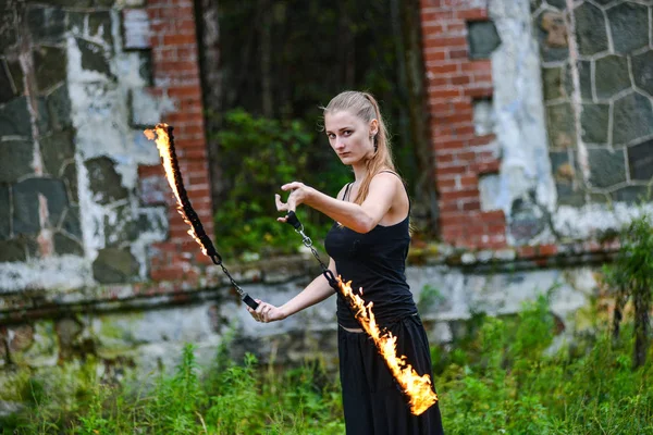 Girl in a black suit with flaming torches . — Stock Photo, Image