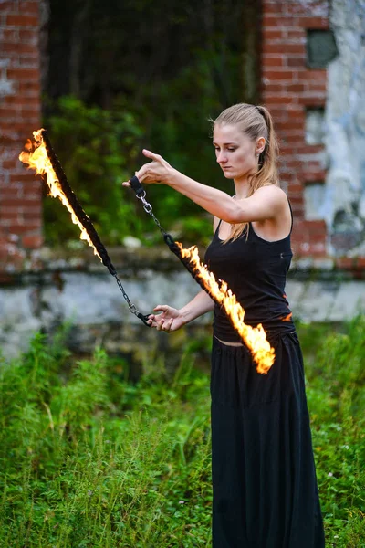 Girl in a black suit with flaming torches . — Stock Photo, Image