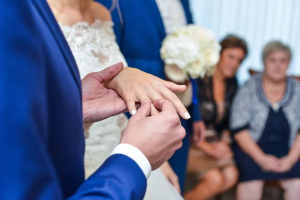 Huwelijk handen met ringen. birde draagt de ring aan de vinger van de bruidegom — Stockfoto