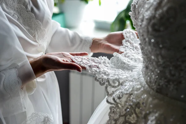 Bruidsmeisje houden van bruiden trouwjurk — Stockfoto