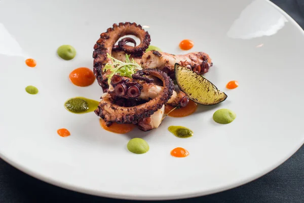 close up of cooked octopus on a white plate