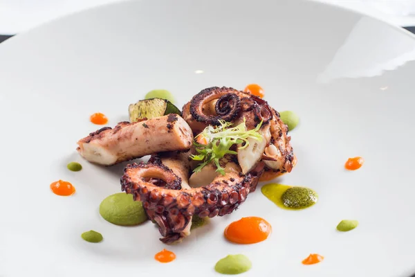 close up of cooked octopus on a white plate