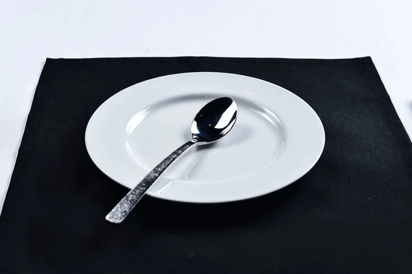 Bílá deska s nožem a vidličkou na černé ubrousek — Stock fotografie