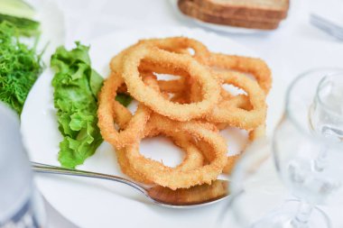 Derin meyilli kızarmış kalamar halkaları kalamar plaka üzerinde yeşil salata ile