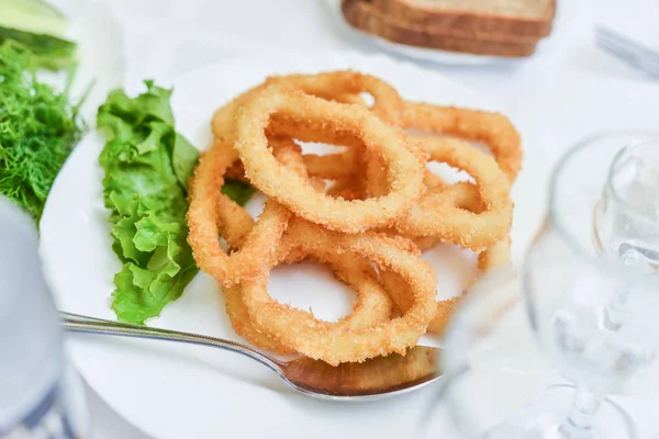 Derin meyilli kızarmış kalamar halkaları kalamar plaka üzerinde yeşil salata ile