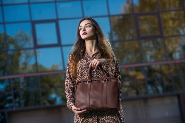 güzel genç kadın elbiseli bir deri çanta ile poz