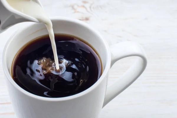 Milch zu einer Tasse Kaffee hinzufügen — Stockfoto