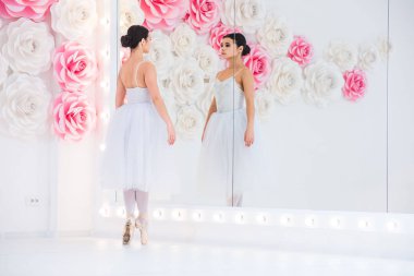 Genç ve inanılmaz güzel balerin ışıkla dolu beyaz bir stüdyoda poz veriyor ve dans ediyor..