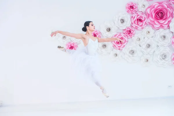 Ung og utrolig vakker ballerina poserer og danser i et hvitt studio fullt av lys . – stockfoto
