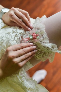 Gelin jartiyer bacak. Yatağın üstüne oturan ve düğün jartiyer üzerinde koyarak güzel gelin. Çorap gelinin. Seksi Gelin jartiyer Beyaz kurdele ve yay ile gösterilen gelinlik içinde. Düğün hazırlığı