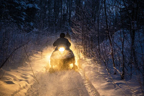 Snöskoter på kvällen går genom vinterskogen. Strålkastare. nattväg genom vinterskogen. snöskoter på natten — Stockfoto