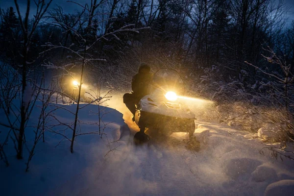 Вечером снегоход проходит через зимний лес. фары. ночная дорога через зимний лес. снегоход ночью — стоковое фото