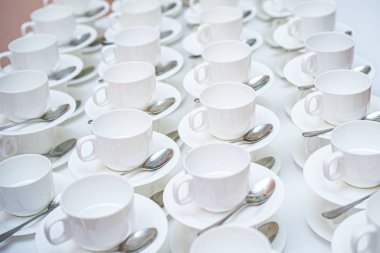 Bir sürü beyaz kahve fincanı. Çay ya da kahve için boş beyaz fincanlar halinde dizilmiş pek çok kişinin üst görüntüsü