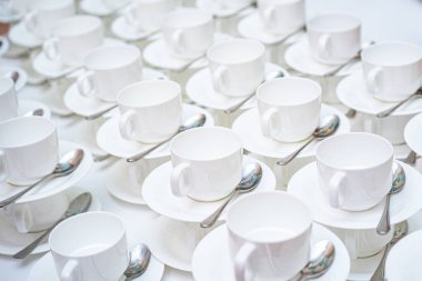 Bir sürü beyaz kahve fincanı. Çay ya da kahve için boş beyaz fincanlar halinde dizilmiş pek çok kişinin üst görüntüsü
