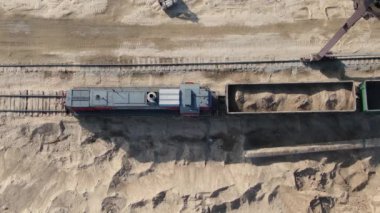 Kariyer kazıcılarının yardımıyla vagonlara kum yüklüyorlar.