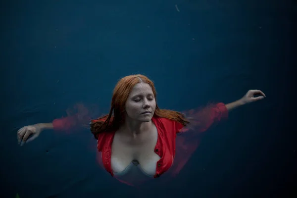 Meisje Met Rood Haar Een Rode Jurk Zit Het Water Stockafbeelding