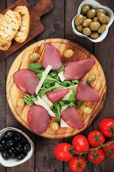 Charcuterie bord met Italiaanse bresaola genezen vlees, raketsla en kaas — Stockfoto