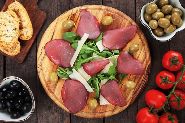 Uzeniny deska s Italská bresaola uzený maso, rukolou a sýrem — Stock fotografie