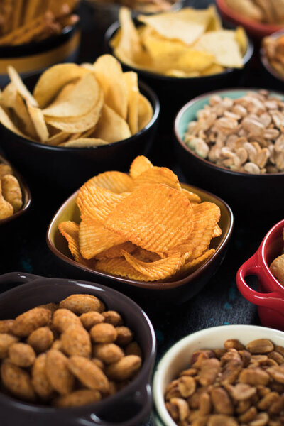 Соленые закуски, включая арахис, картофельные чипсы и крендельки, подаются в качестве праздничной еды в мисках
