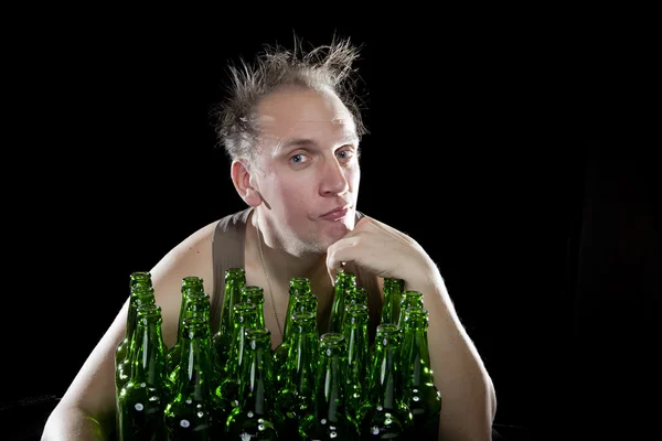 El hombre feliz y borracho cerca de botellas de cerveza vacías — Foto de Stock