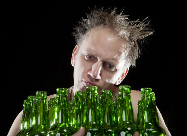 El borracho se sienta con un montón de botellas de cerveza, una resaca — Foto de Stock