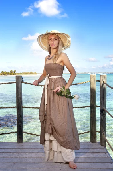 Die schöne Frau in einem langen Kleid auf einer Holzplattform über dem Meer — Stockfoto