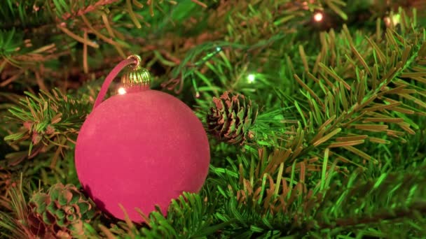 Bola de Ano Novo vermelho contra o fundo da grinalda decorada de uma árvore de Natal — Vídeo de Stock