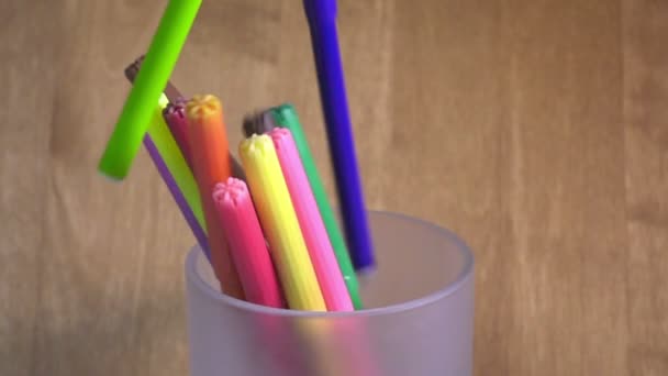 Яркие ручки войлока падают в стакан, замедленная съемка — стоковое видео