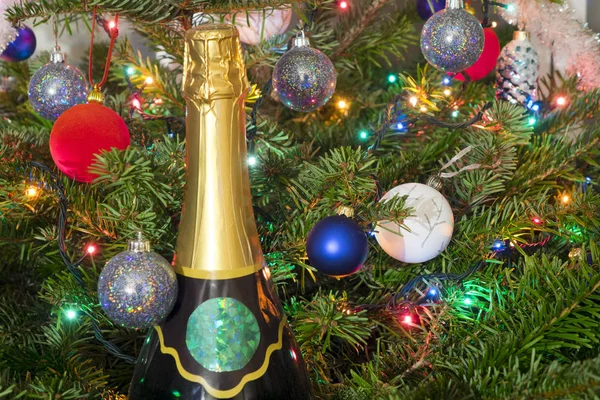 Новогодние балы на новогодней елке и огромная бутылка игристого вина — стоковое фото