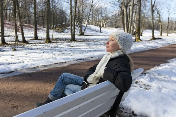 A mulher bonita jovem tem um resto em um banco no par de inverno — Fotografia de Stock