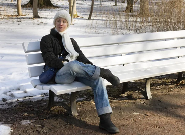 若い美しい女性冬パーのベンチに残りの部分には — ストック写真