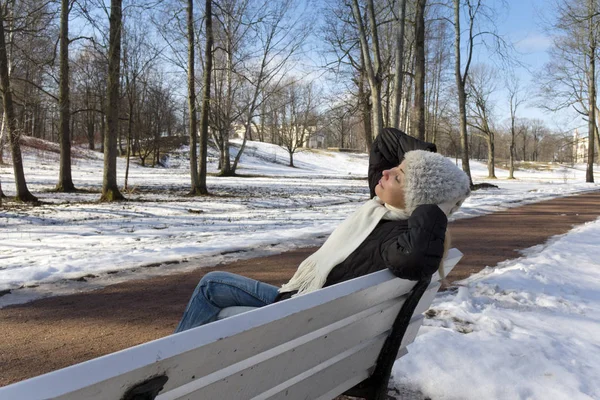 A mulher bonita jovem tem um resto em um banco no par de inverno — Fotografia de Stock