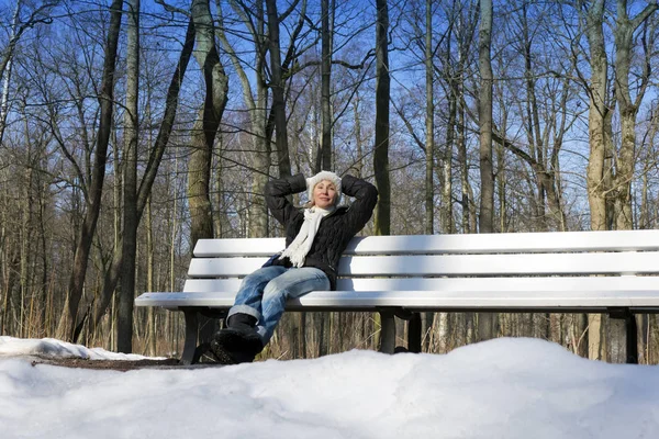 A mulher bonita jovem tem um resto em um banco no par de inverno — Fotografia de Stock