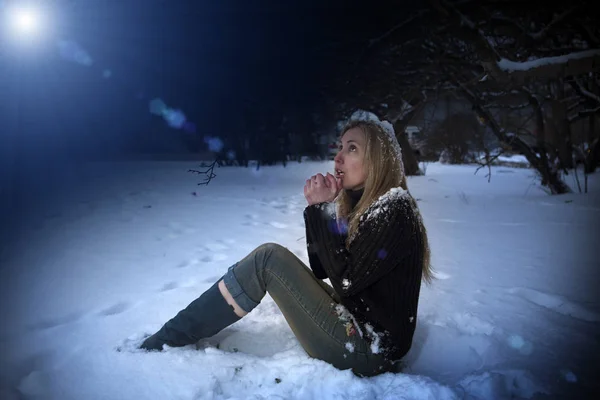 La jeune belle femme gelée est assise dans la neige dans le parc de nuit — Photo