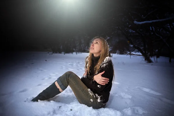 젊은 아름 다운 냉동된 여자 밤 공원에 눈에 앉아 — 스톡 사진
