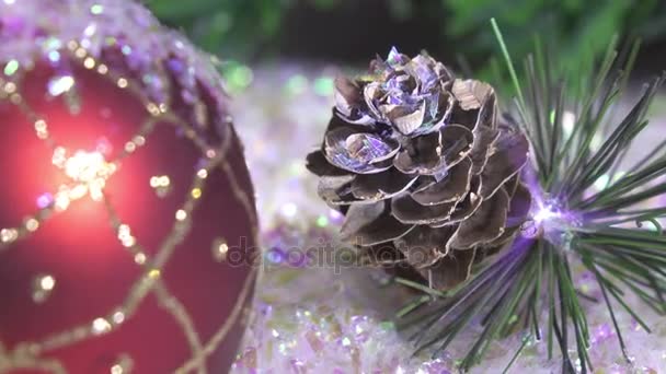 Новогодние шары лежат на снегу на фоне елки — стоковое видео