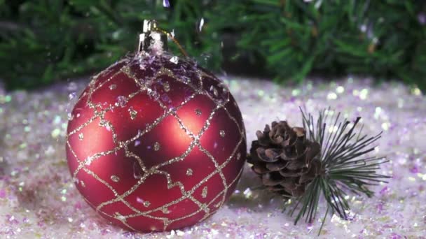La nieve cae poco a poco sobre las bolas de Año Nuevo sobre el fondo del abeto de Navidad. cámara lenta — Vídeos de Stock