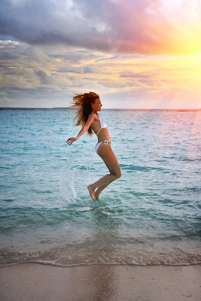 Maldivas. A silhueta a jovem esbelta felizmente pula no mar em um pôr-do-sol — Fotografia de Stock