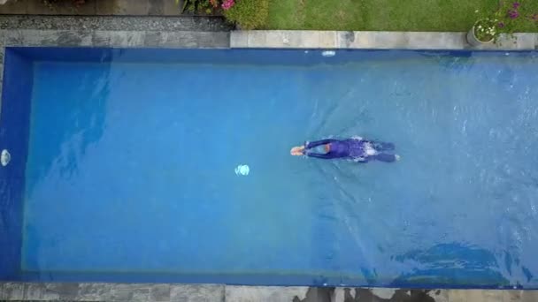 Mulher atraente em uma roupa de banho muçulmana burkini espirra água na piscina e nada — Vídeo de Stock