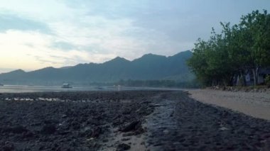 Taşlı sahil ve dağların üzerinde bir gün batımı. Endonezya. Drone görünümünden Bali.Aerial