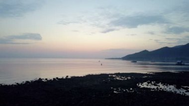 Taşlı sahil ve dağların üzerinde bir gün batımı. Endonezya. Drone görünümünden Bali.Aerial