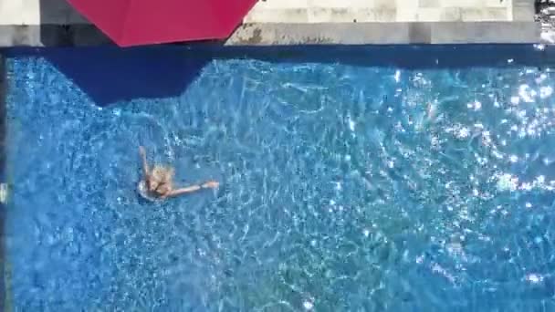The young beautiful woman swims in the pool in a tropical garden, Aerial view from drone — стоковое видео