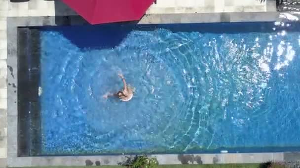 Die junge schöne Frau schwimmt im Pool in einem tropischen Garten, Luftaufnahme von der Drohne — Stockvideo