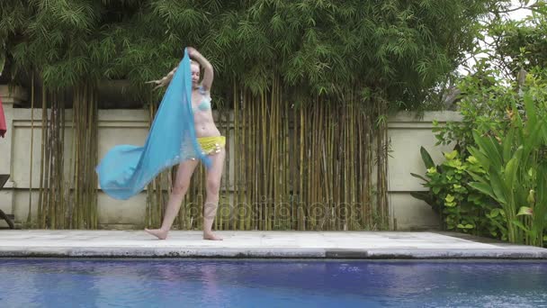 Young slender woman dances an oriental dance near pool in tropical resort — Stock Video